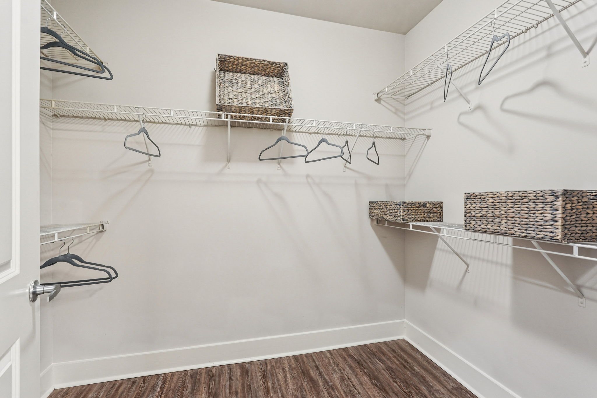 A white closet with a wooden floor and a white door.